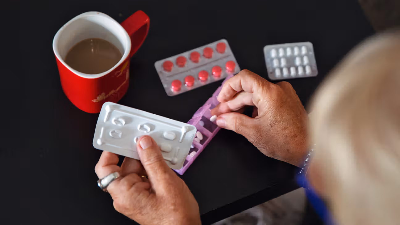 Older female organizing medication pills