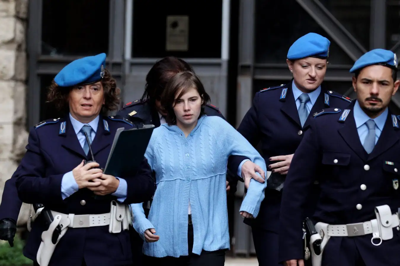 PERUGIA, ITALY - NOVEMBER 24: Amanda Knox (C) is led away from Perugia's court of Appeal by police officers after the first session of her appeal against her murder conviction on November 24, 2010 in Perugia, Italy. American Amanda Knox and her Italian ex-boyfriend Raffaele Sollecito were convicted of the murder of Ms Knox's former British flatmate Meredith Kercher in 2007. Their trial took place in December 2009 with Knox and Sollecito receiving sentences of 26 and 25 years respectively. Rudy Guede, an unemployed man from Ivory Coast, was also convicted of the Meredith Kercher's murder. The case is also forming the basis for a film currently being shot in Italy entitled 'The Amanda Knox Story', with American actress Hayden Panettiere cast as Amanda Knox. (Photo by Oli Scarff/Getty Images)
