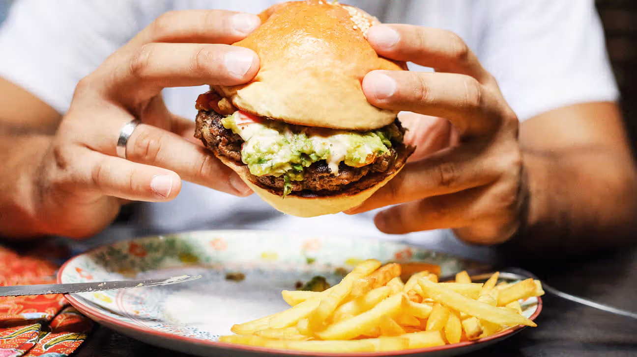 Closeup of male holding a cheeseburger with fries
