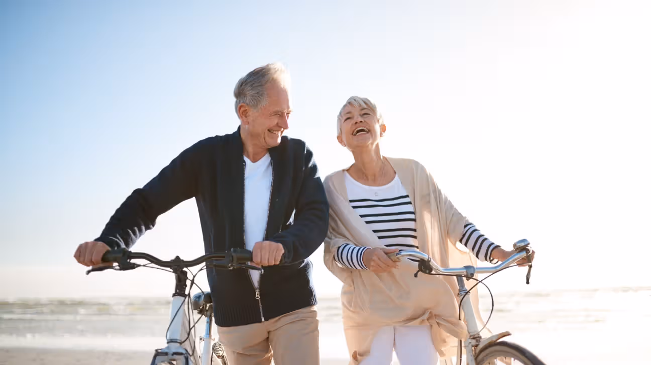 A senior man and woman walking alongside bikes.