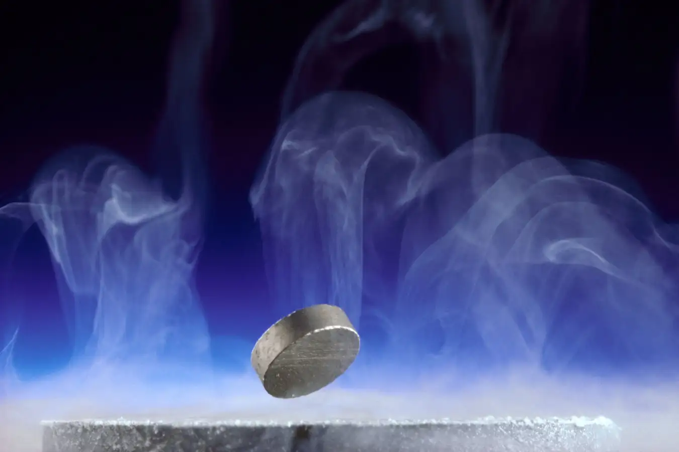 A superconducting pellet of ytrrium barium copper oxide composite. A small metallic disc levitates over a platform, shrouded in steam