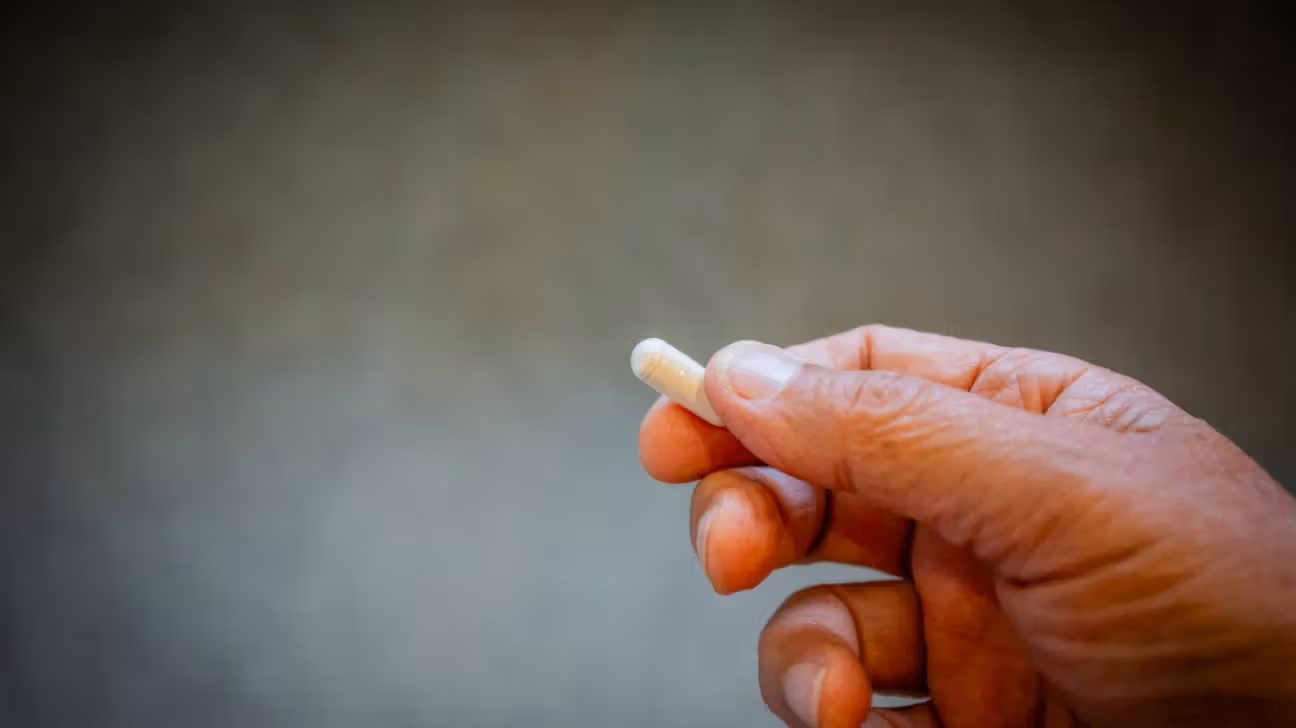 Closeup of a person's hand holding a pill.