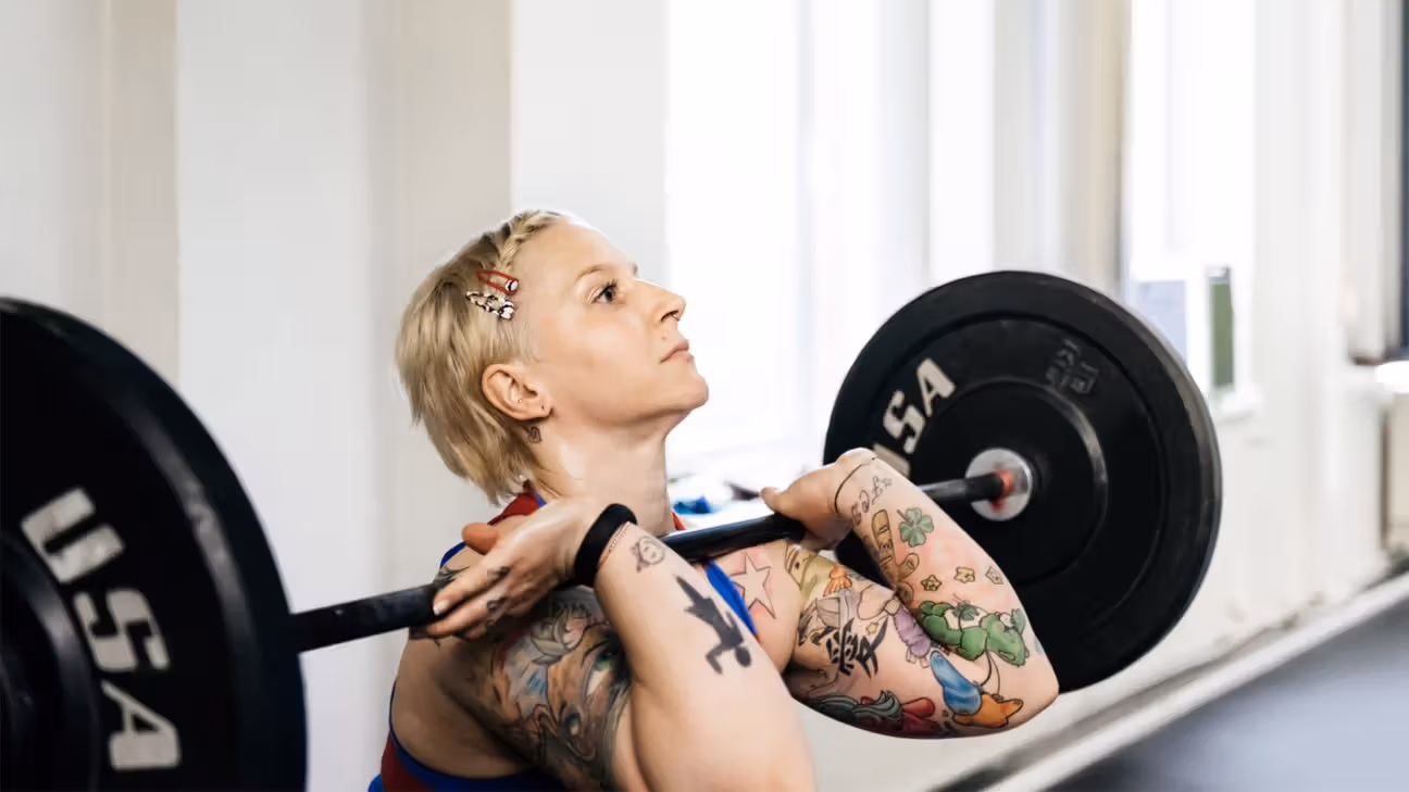 Tattooed female lifting weights in a gym